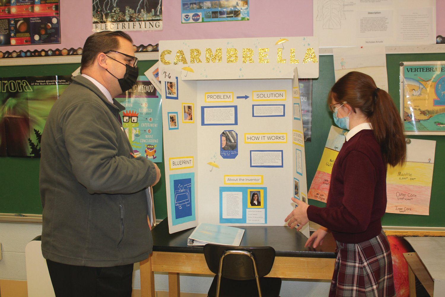 INVENTION INSPECTION: Channel 12’s T.J. DelSanto checks out Saint Rocco School student Kate Gorgievski’s project for the Annual Invention Convention. (Photo courtesy Robin Okolowitcz)